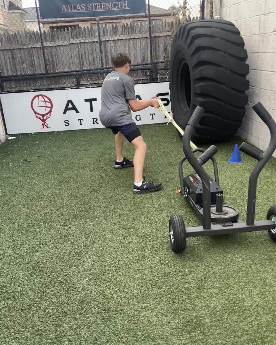 Athlete pulling a weighted sled with a rope on the Atlas Strength turf