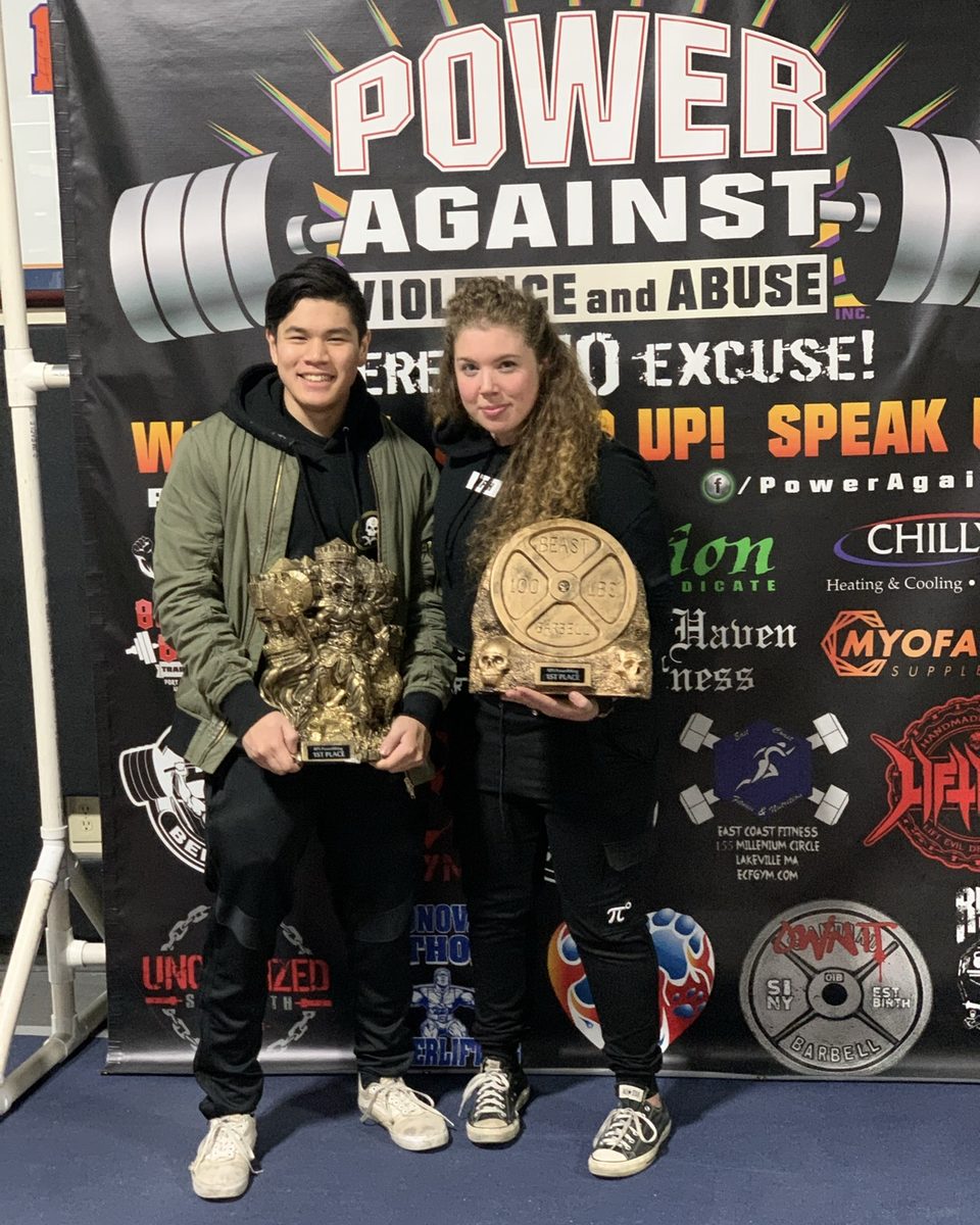 Two Atlas Strength lifters holding first-place powerlifting trophies