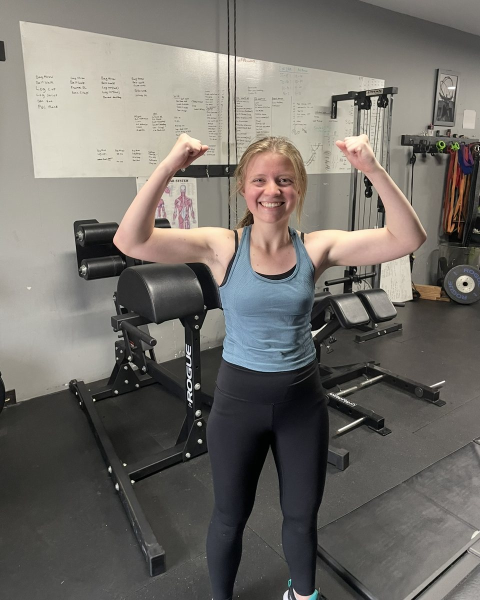 Client flexing and smiling in the gym