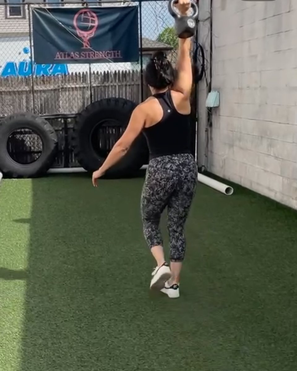 Client doing an overhead kettlebell carry on the turf