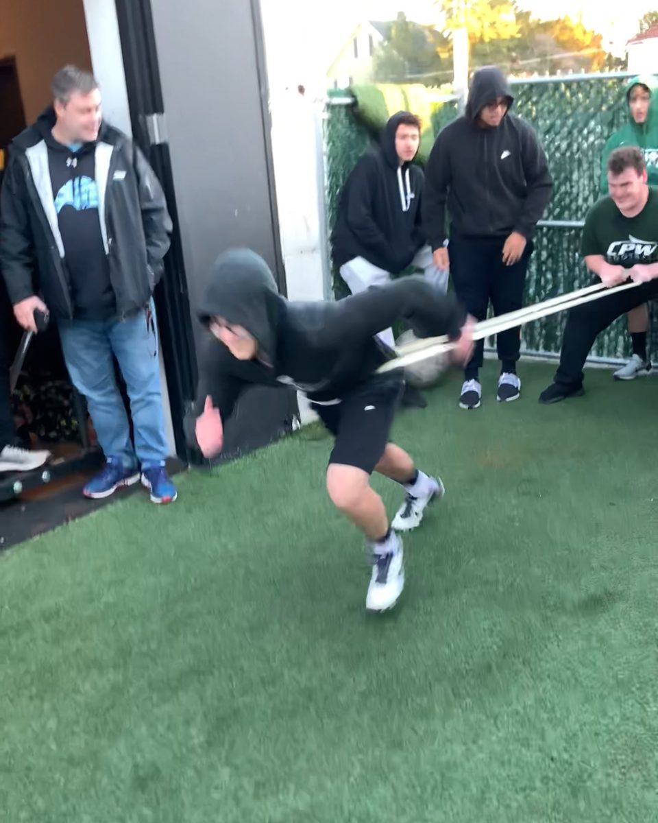 Football players doing resisted band sprints on the turf
