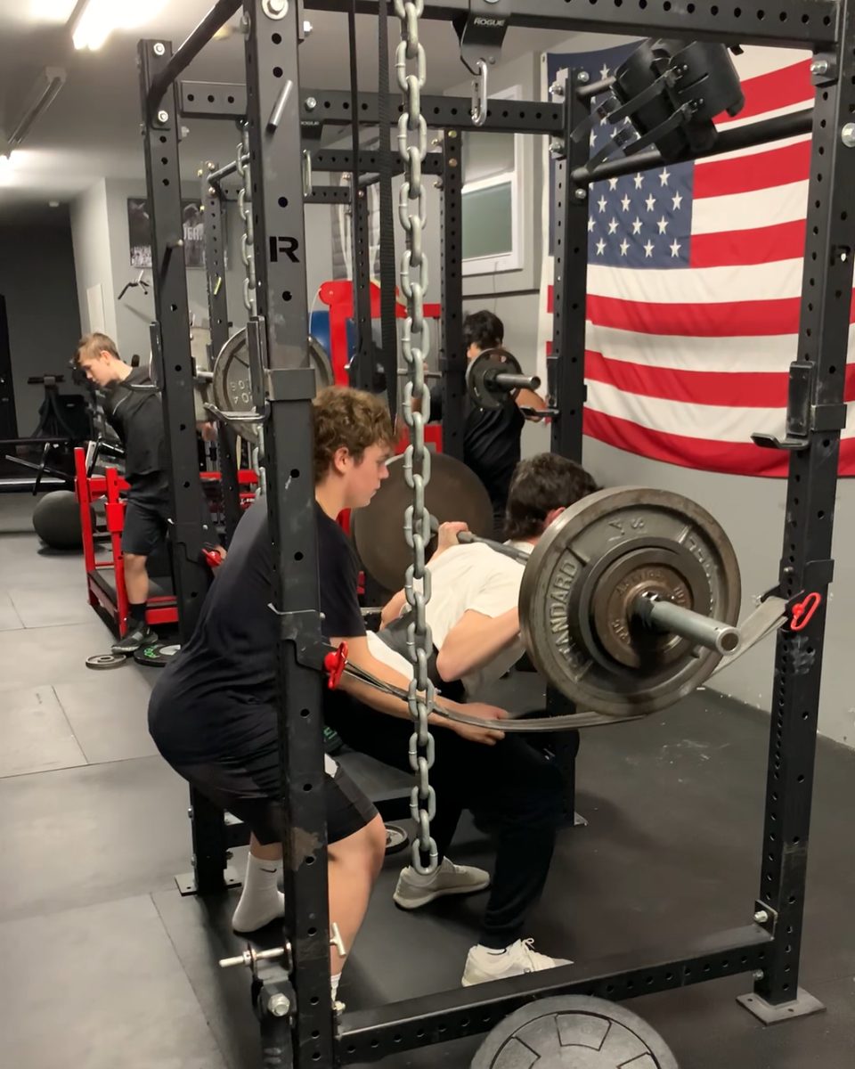High school players squatting in the racks with teammates spotting