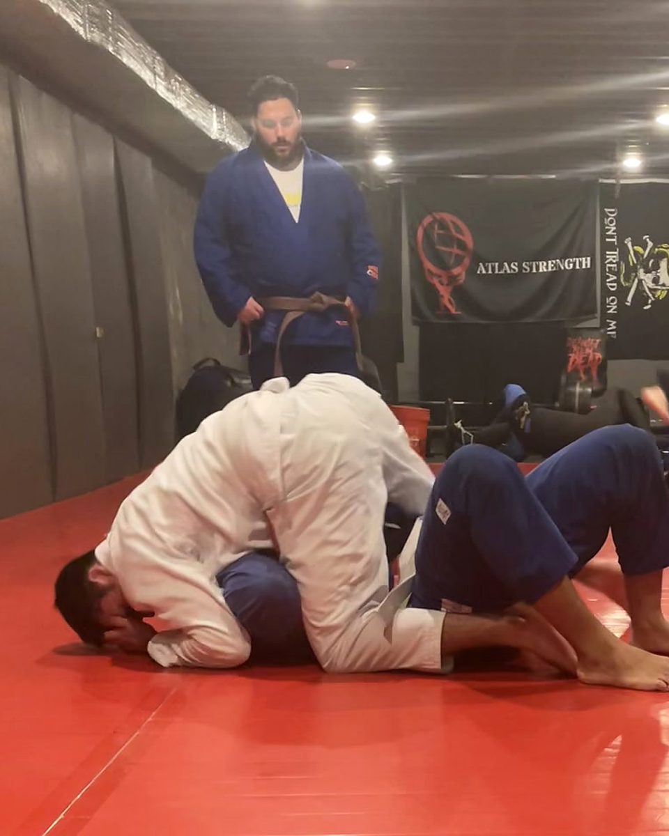 Two people drilling jiu-jitsu in the gi on the red mats