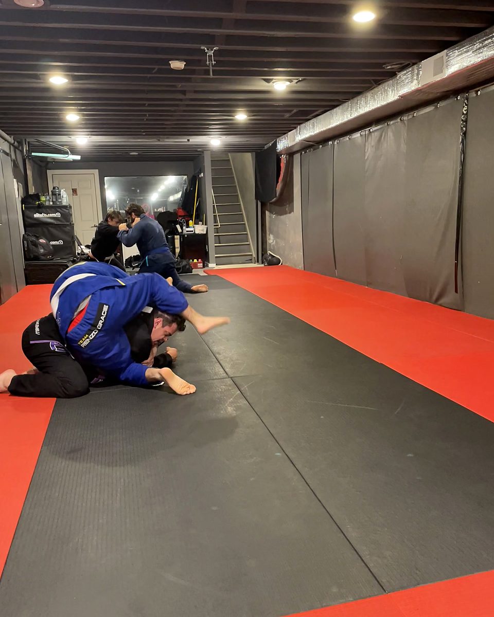 Jiu-jitsu training in the gi with the full matted lower level behind