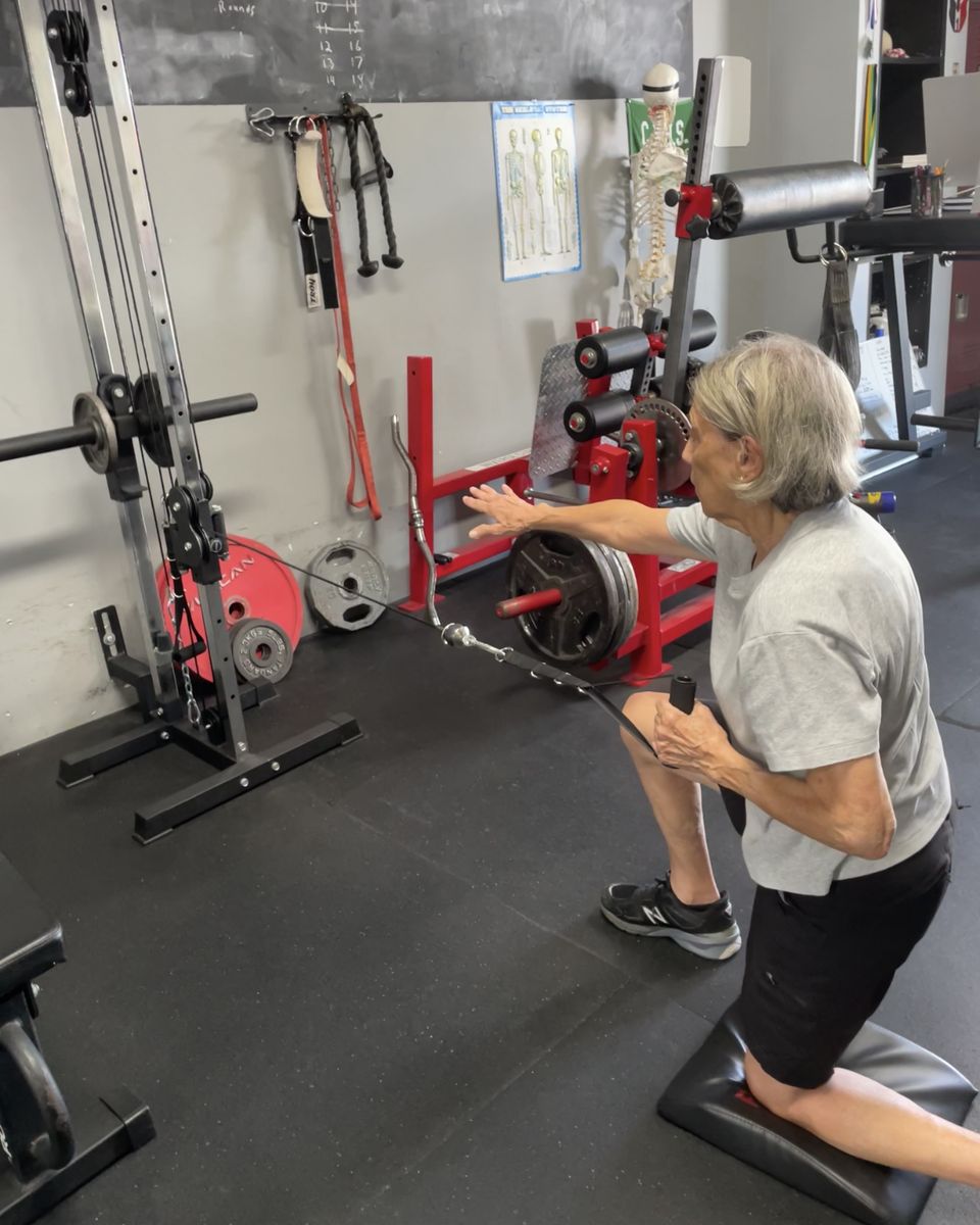 Older client doing a half-kneeling cable row