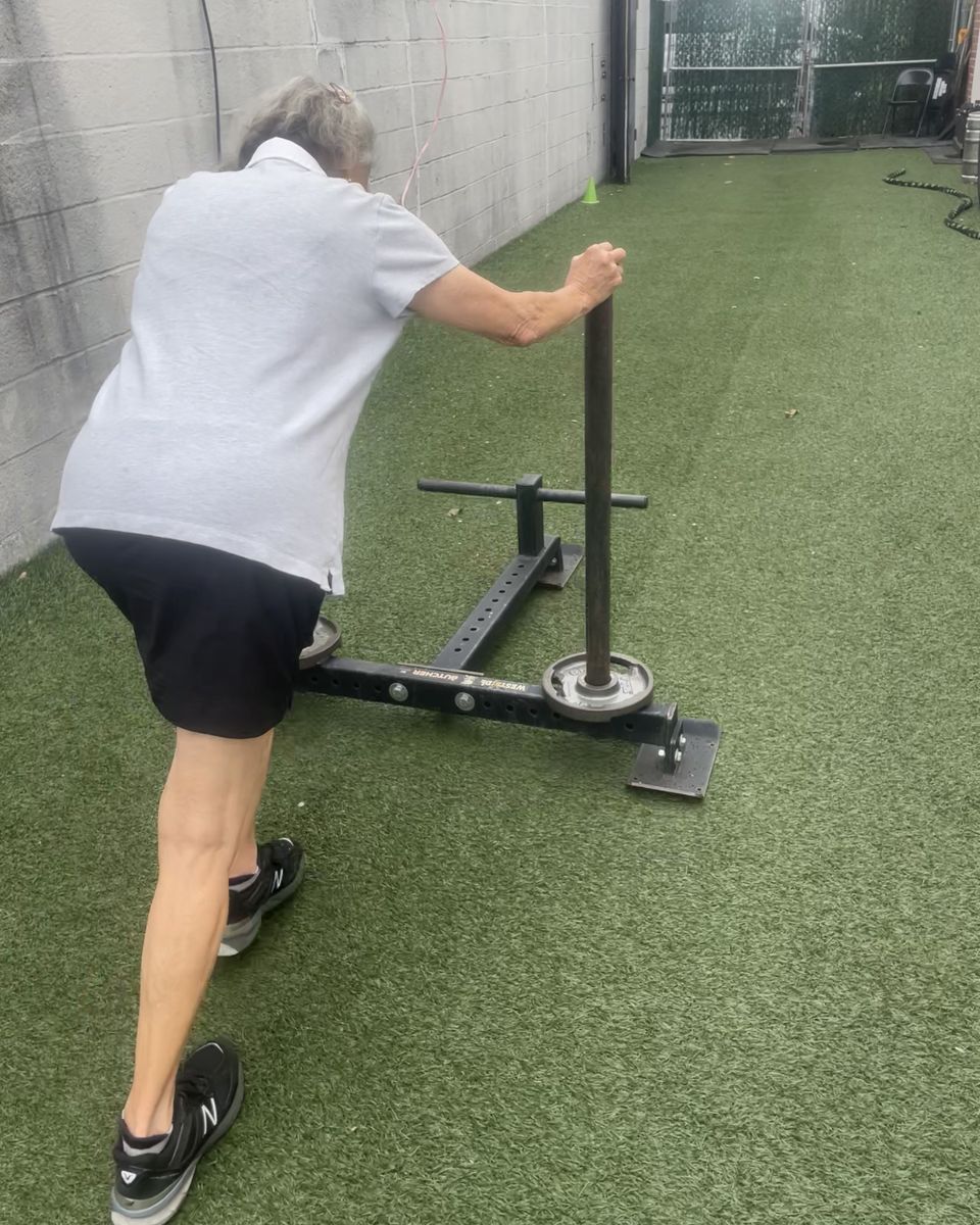 Older client pushing a sled on the turf