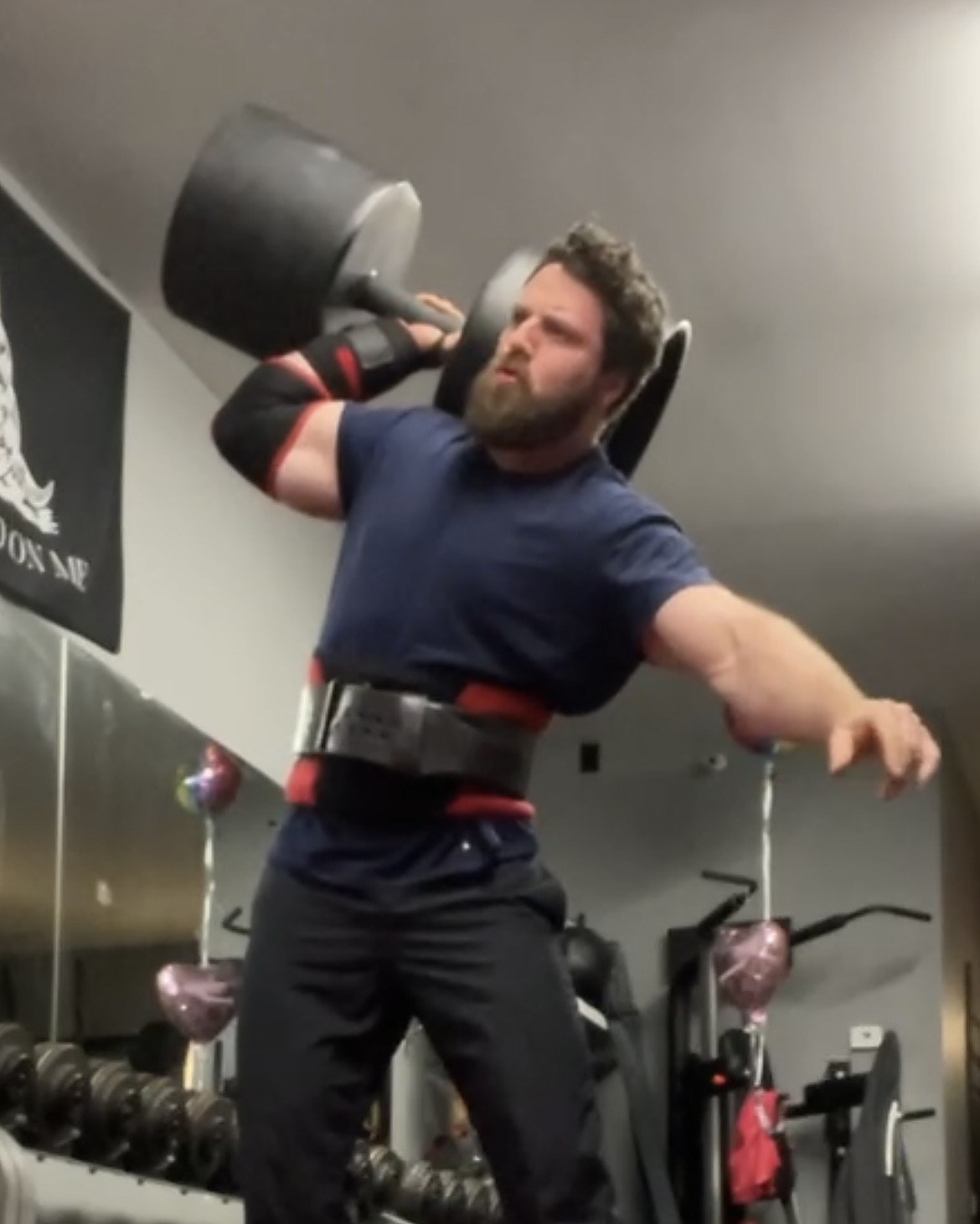 Patrick Rice pressing a circus dumbbell at Atlas Strength