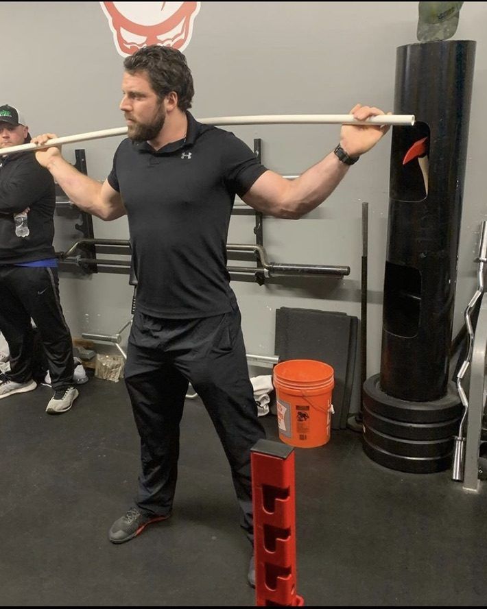 Patrick Rice demonstrating squat position with a dowel