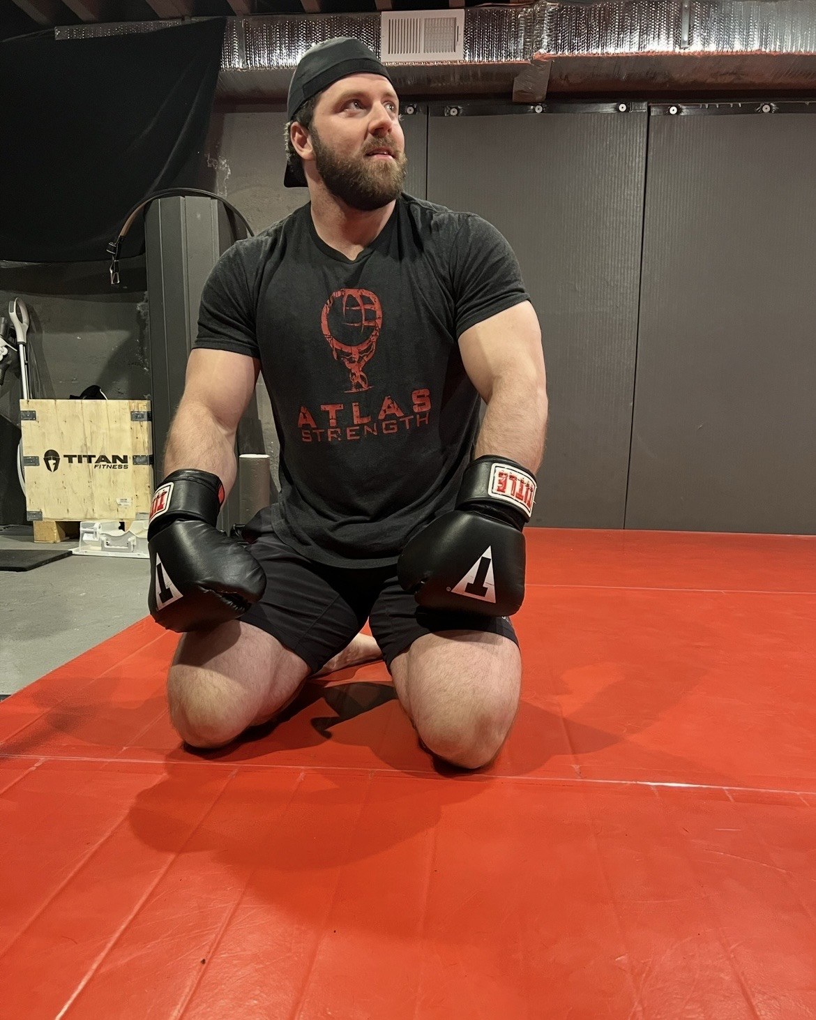 Patrick Rice in boxing gloves on the mats at Atlas Strength
