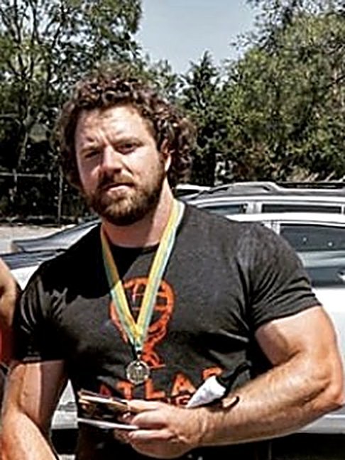 Patrick Rice wearing a competition medal and an Atlas Strength shirt
