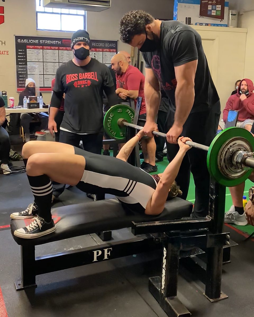 Patrick Rice handing off a bench press to an Atlas Strength lifter at a meet