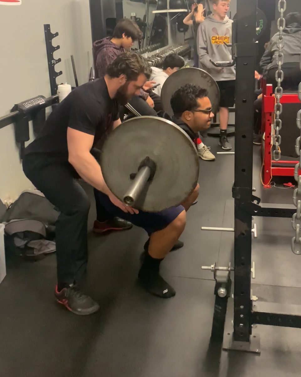 Patrick Rice spotting and cueing a client through a squat