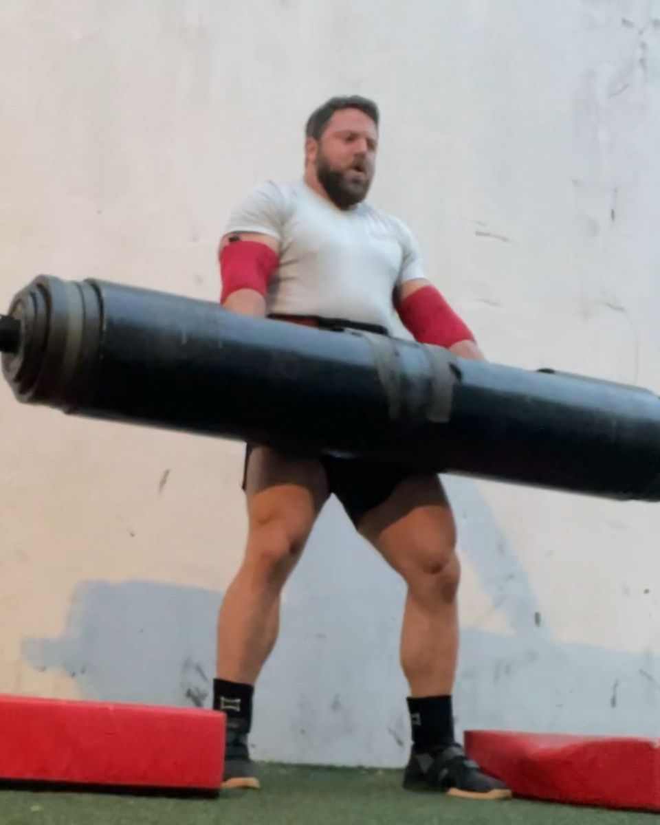 Patrick Rice cleaning a strongman log on the turf