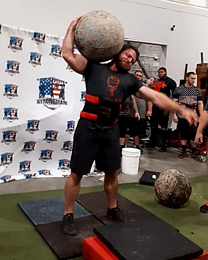 Patrick Rice lifting a stone at a strongman competition