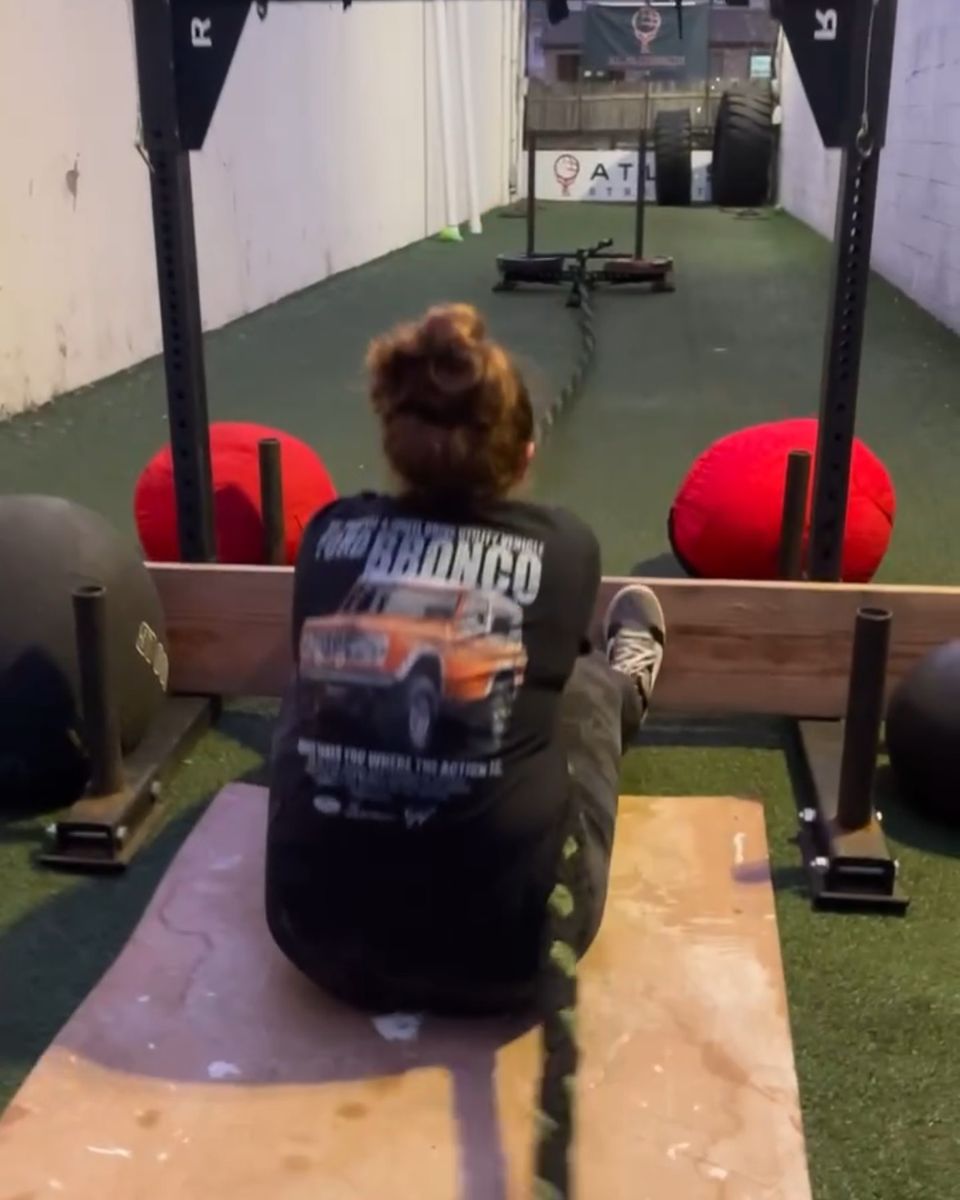 Seated rope pull of a sled on the outdoor turf