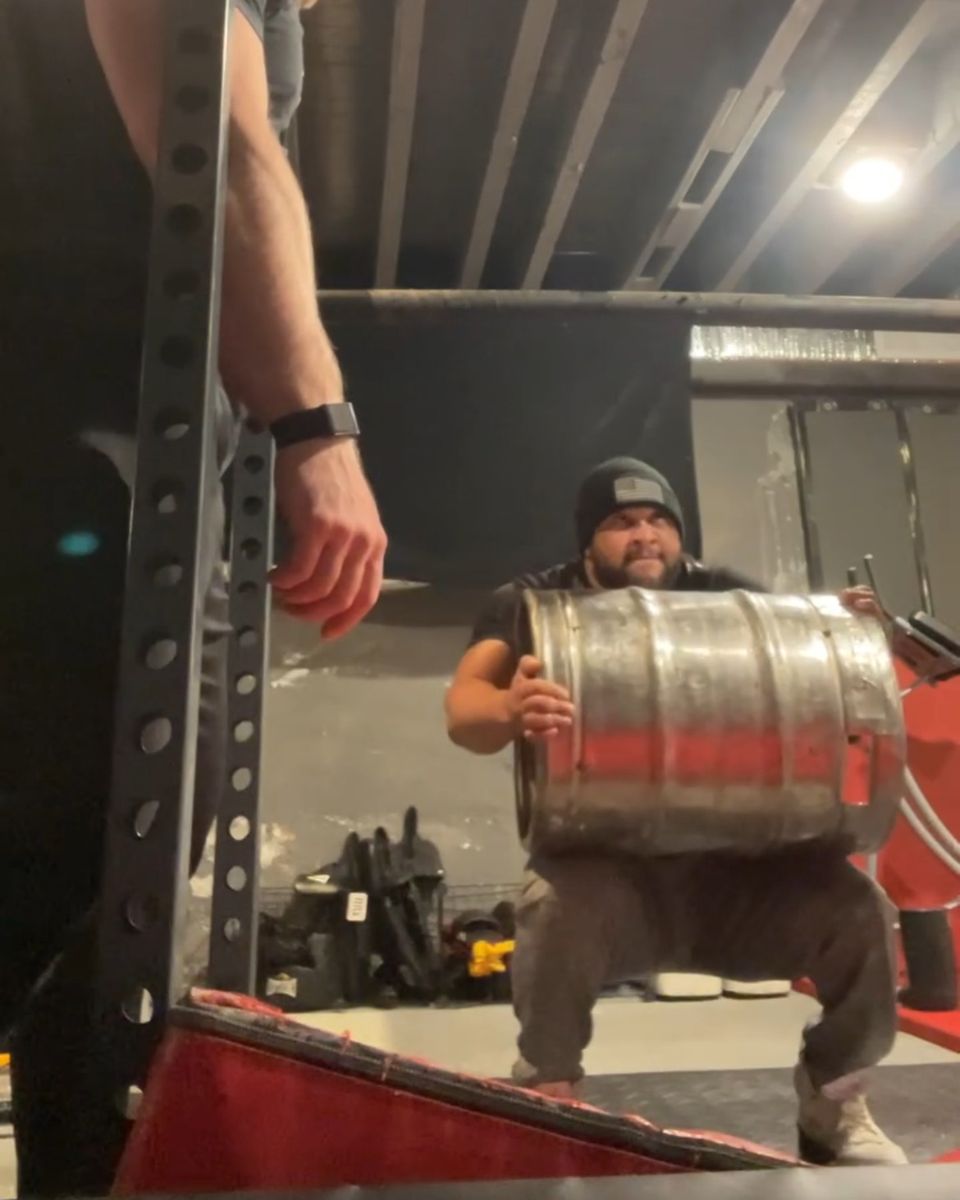Athlete loading a keg while Patrick Rice coaches
