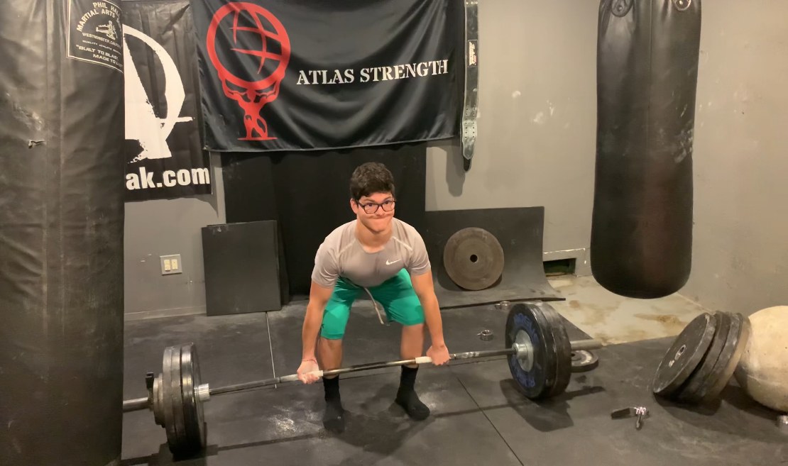 Teen setting up for a deadlift under the Atlas Strength banner