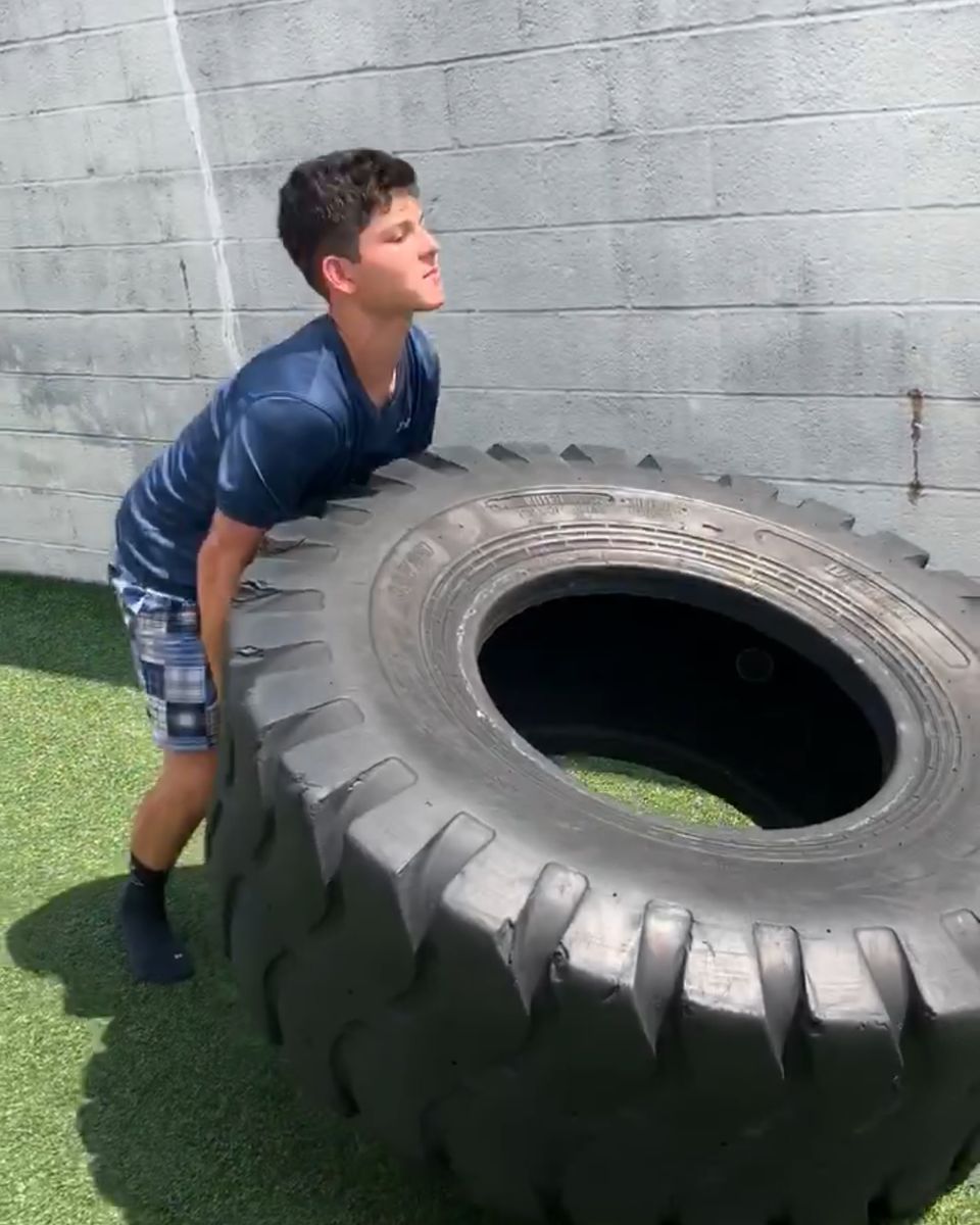 Teen flipping a tire on the outdoor turf