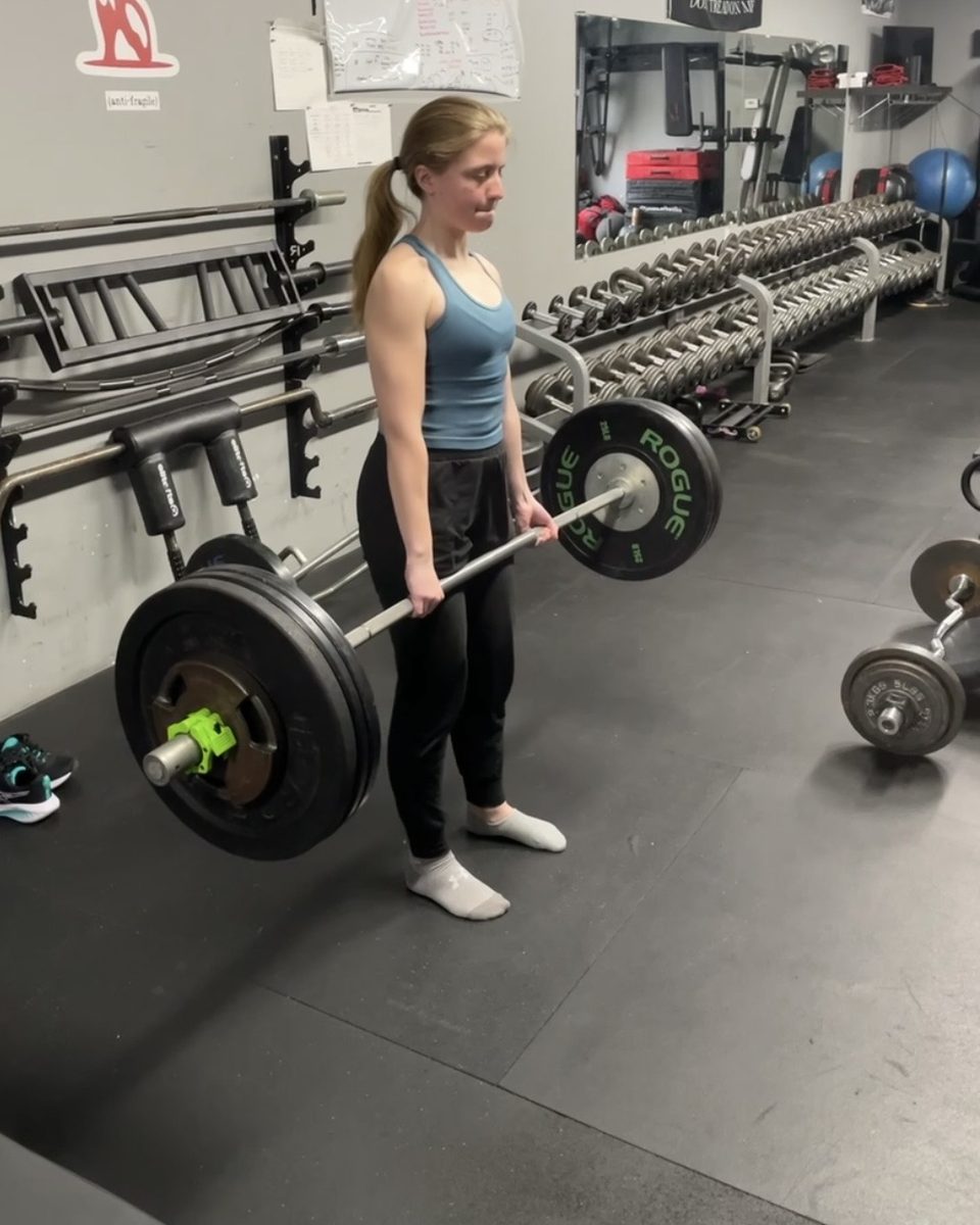 Young woman locking out a trap bar deadlift at Atlas Strength