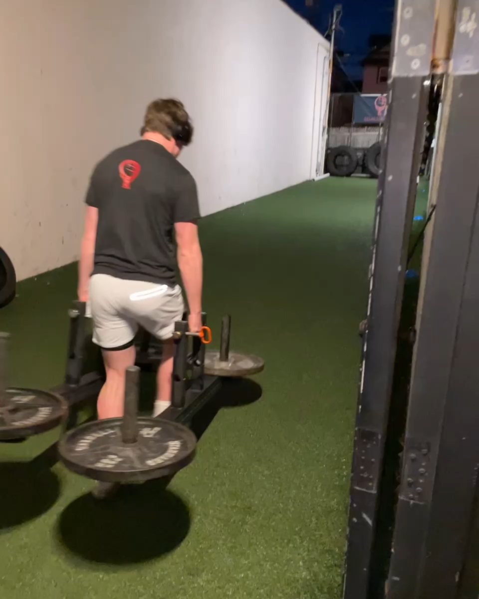 Client pushing a sled on the turf