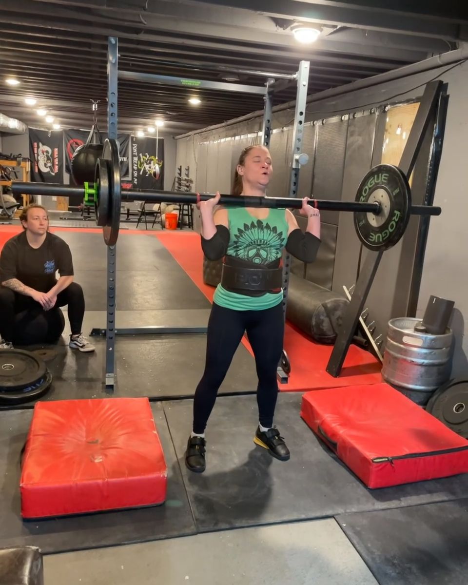 Woman with an axle in the front rack at Atlas Strength