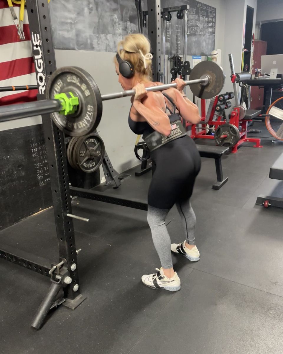 Woman back squatting with a belt at Atlas Strength