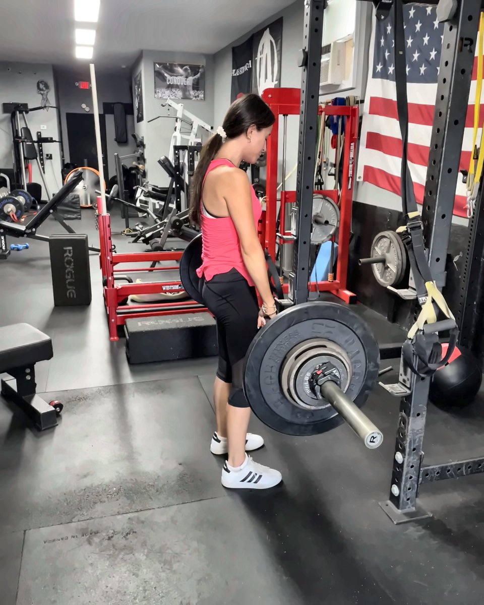 Woman locking out a deadlift on the main floor
