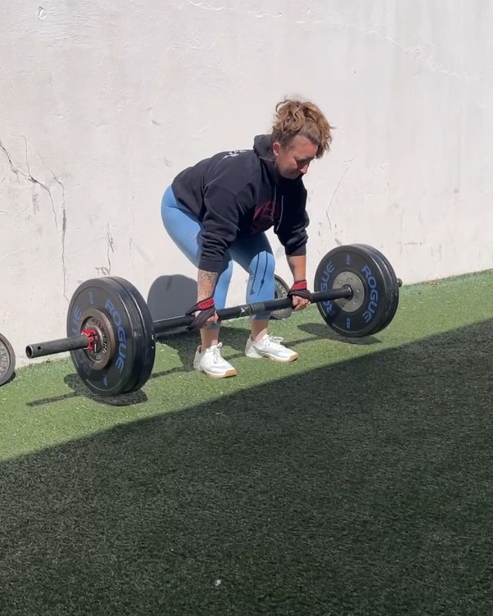 Woman deadlifting on the outdoor turf at Atlas Strength