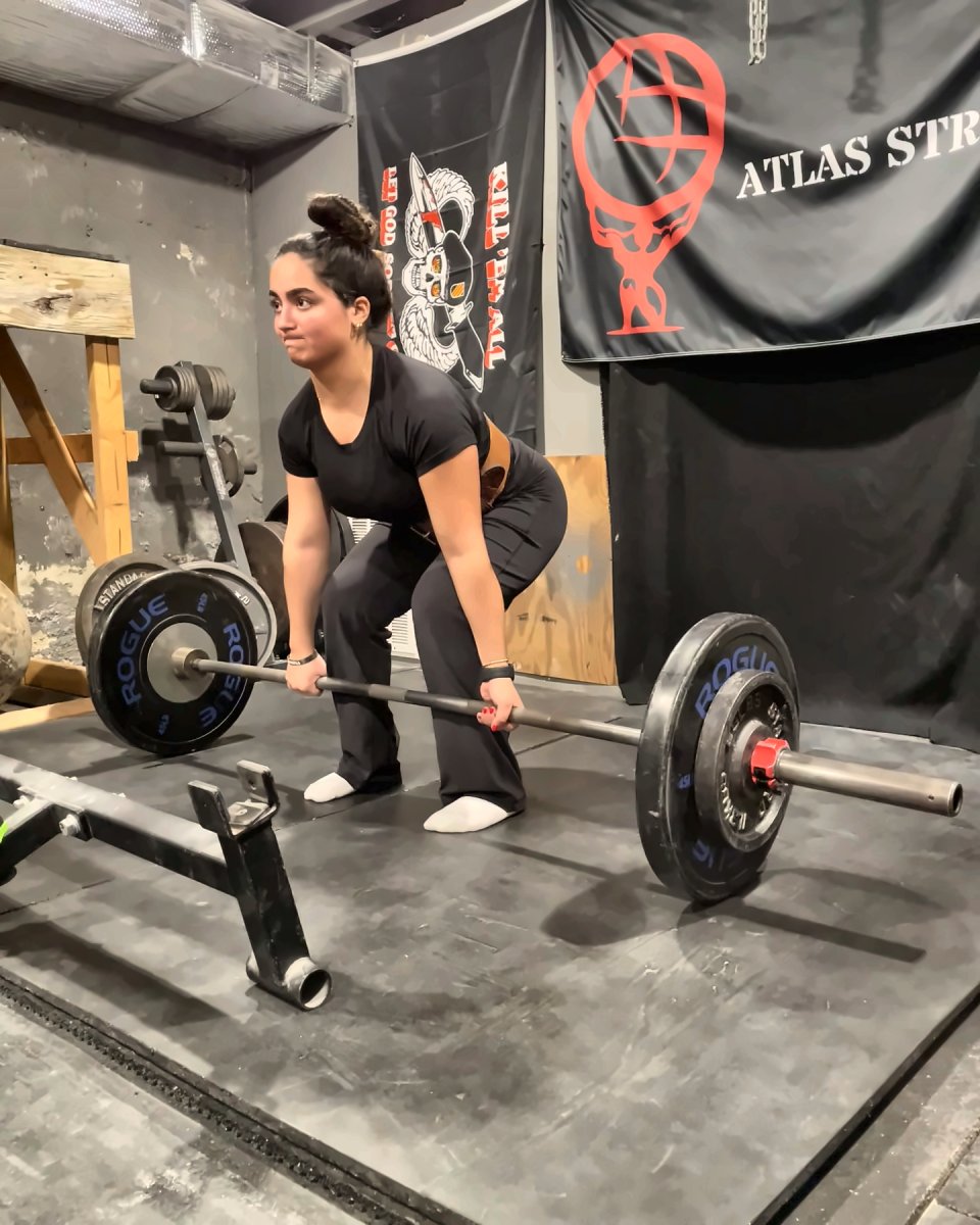 Client setting up for a deadlift under the Atlas Strength banner