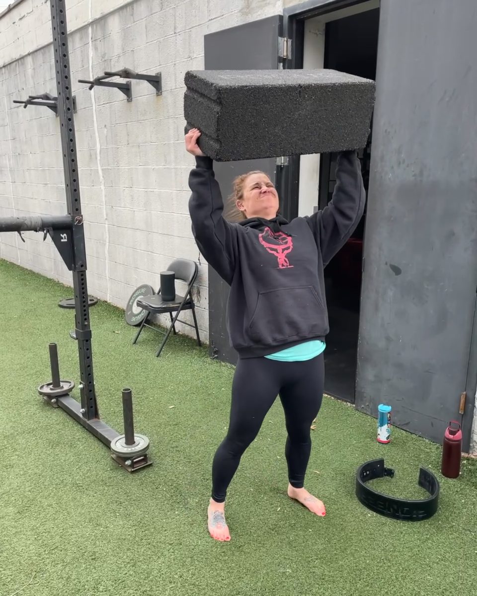 Woman pressing a strongman block overhead at Atlas Strength